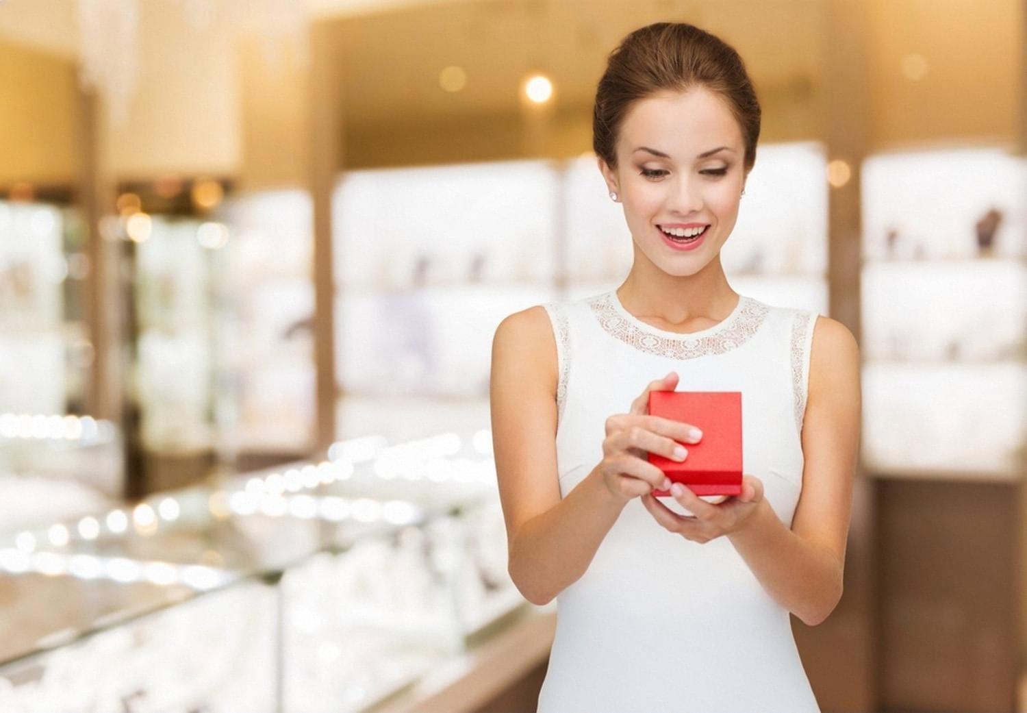 Woman in a jewelry showroom holding a small red box, considering a purchase to store in a safe